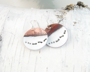 round flame painted and white copper enameled earrings with blackened sterling wire representing running wolves across snow